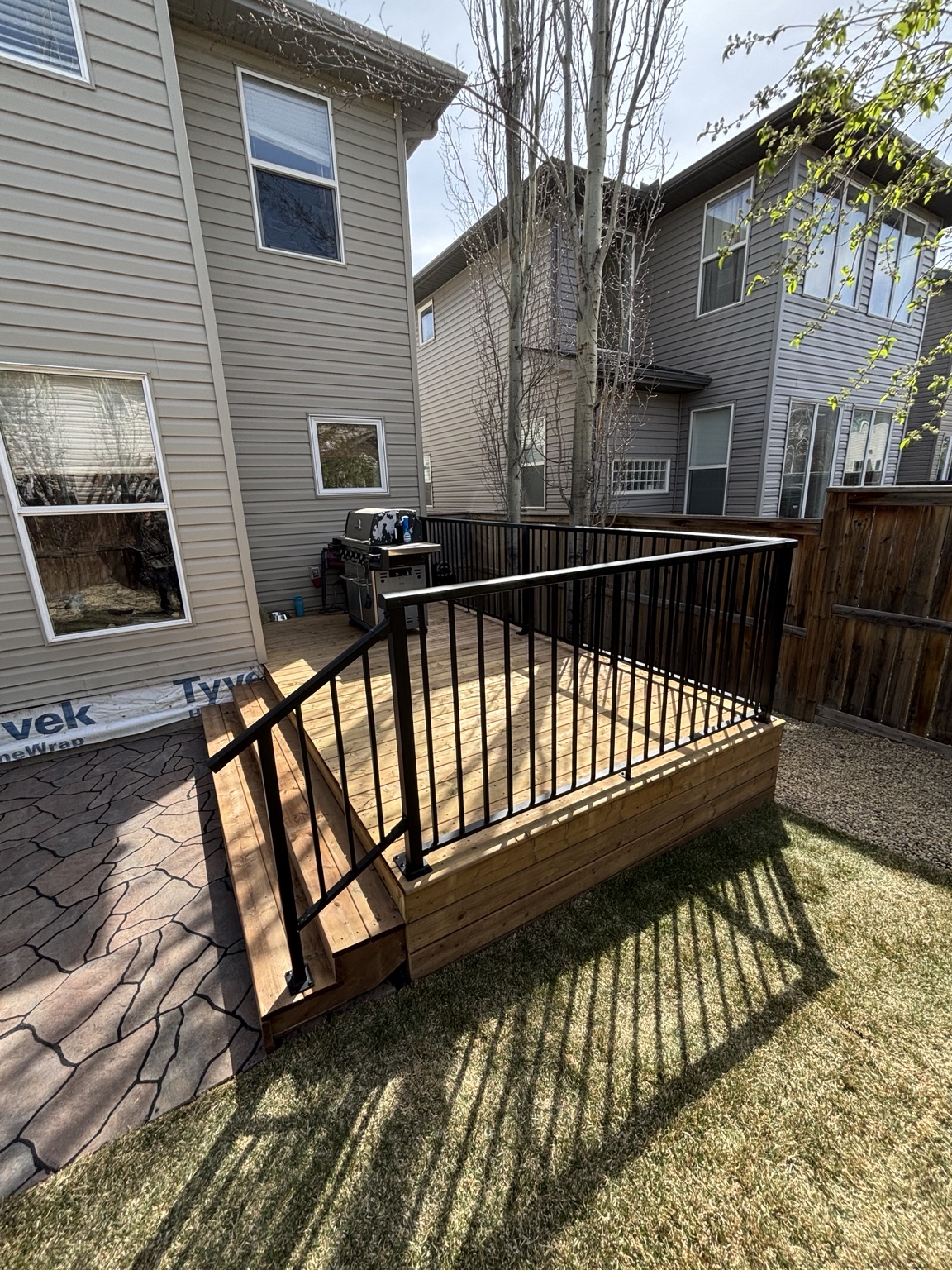 Compact backyard deck finished with black aluminum picket railing