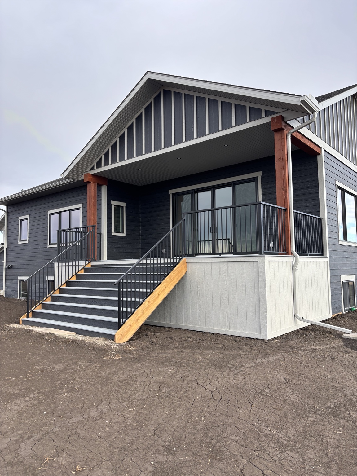 Covered rear entry with black powder-coated aluminum railing and finished stairs