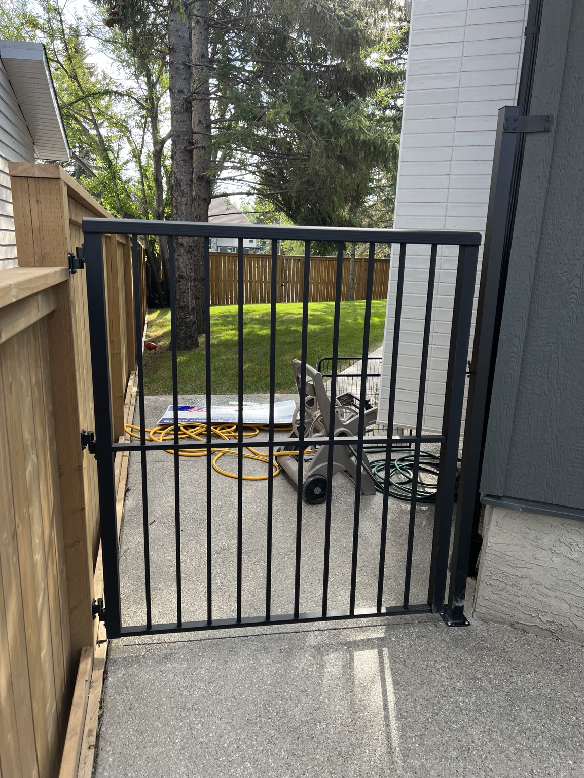 Custom black aluminum safety gate installed beside a home