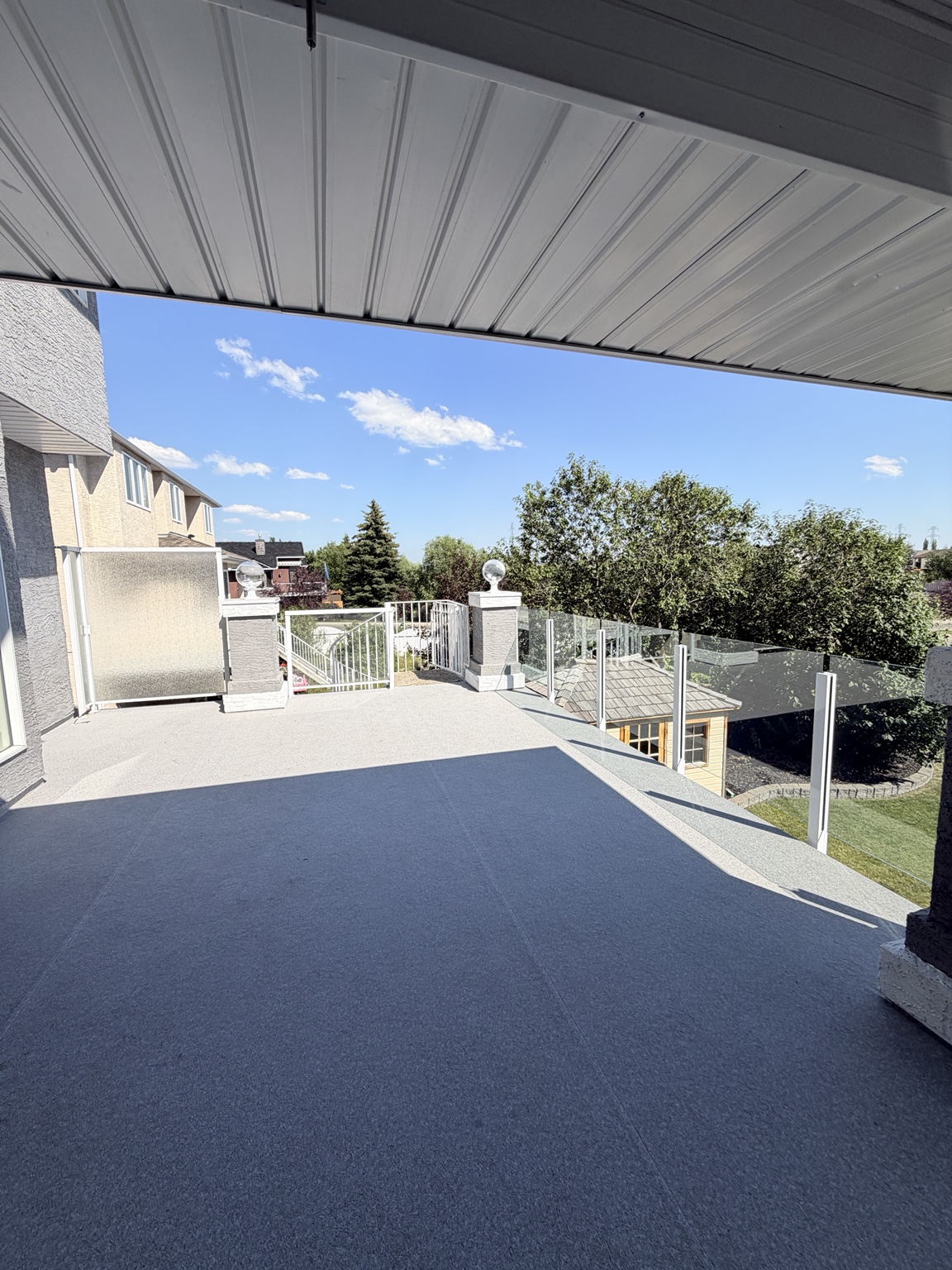 Large covered deck with grey waterproof vinyl and glass railings