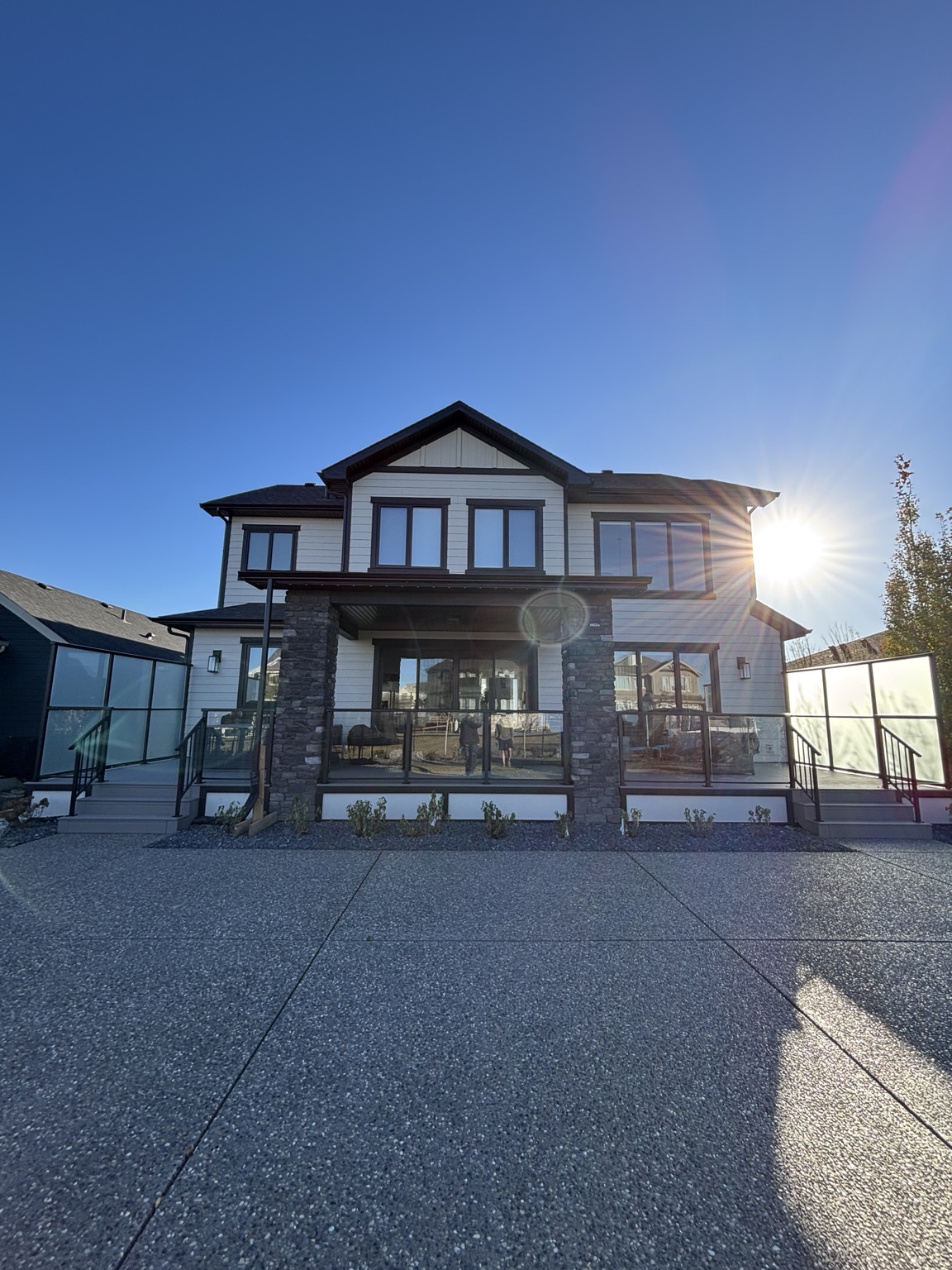Large backyard patio with black powder-coated aluminum and clear glass railing
