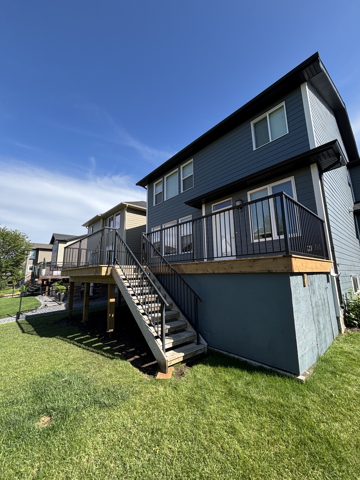 Raised backyard deck with black railing and stair system
