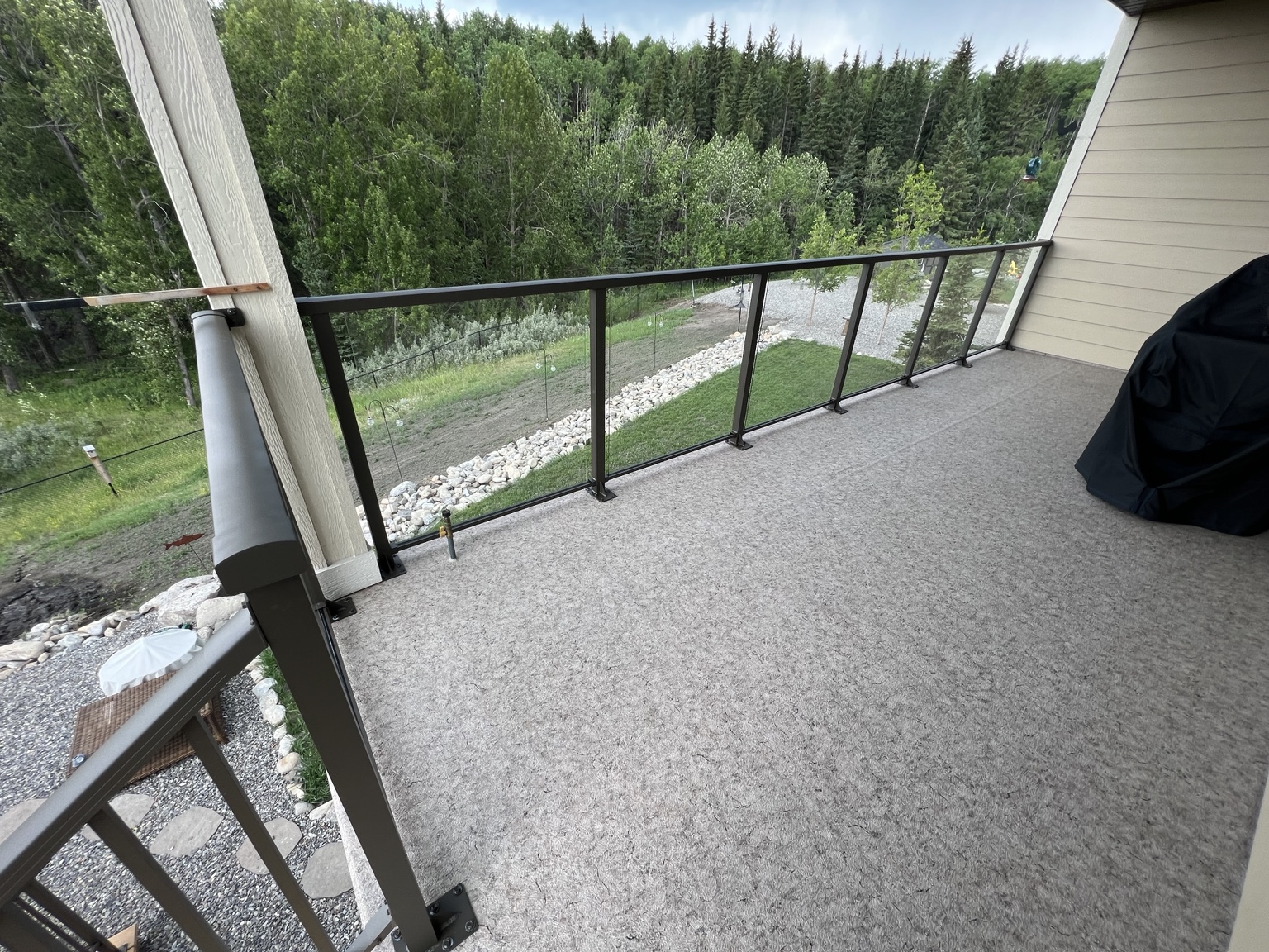 Waterproof vinyl deck with glass railing overlooking a wooded property
