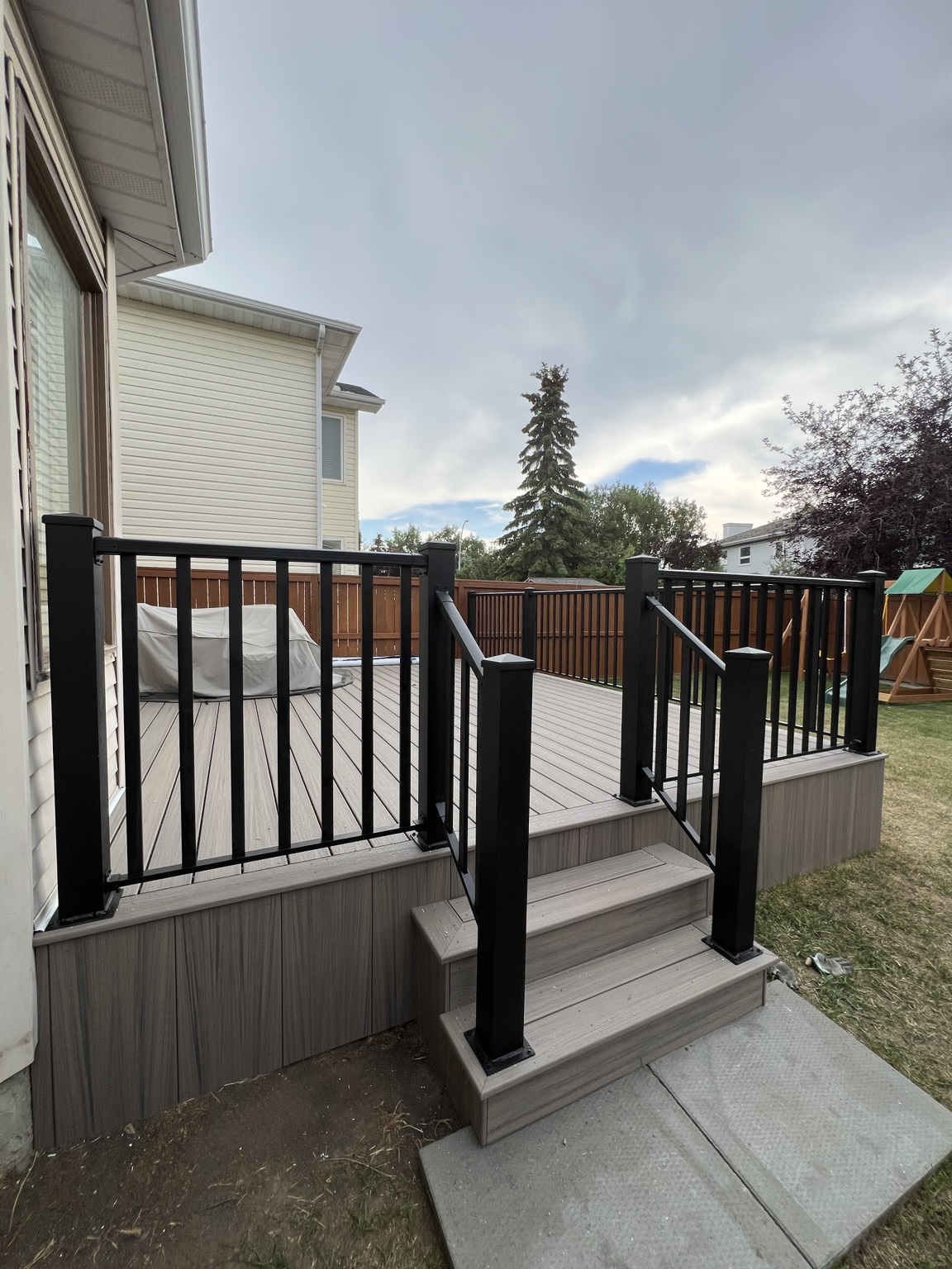 Compact grey deck with black aluminum railing and gate