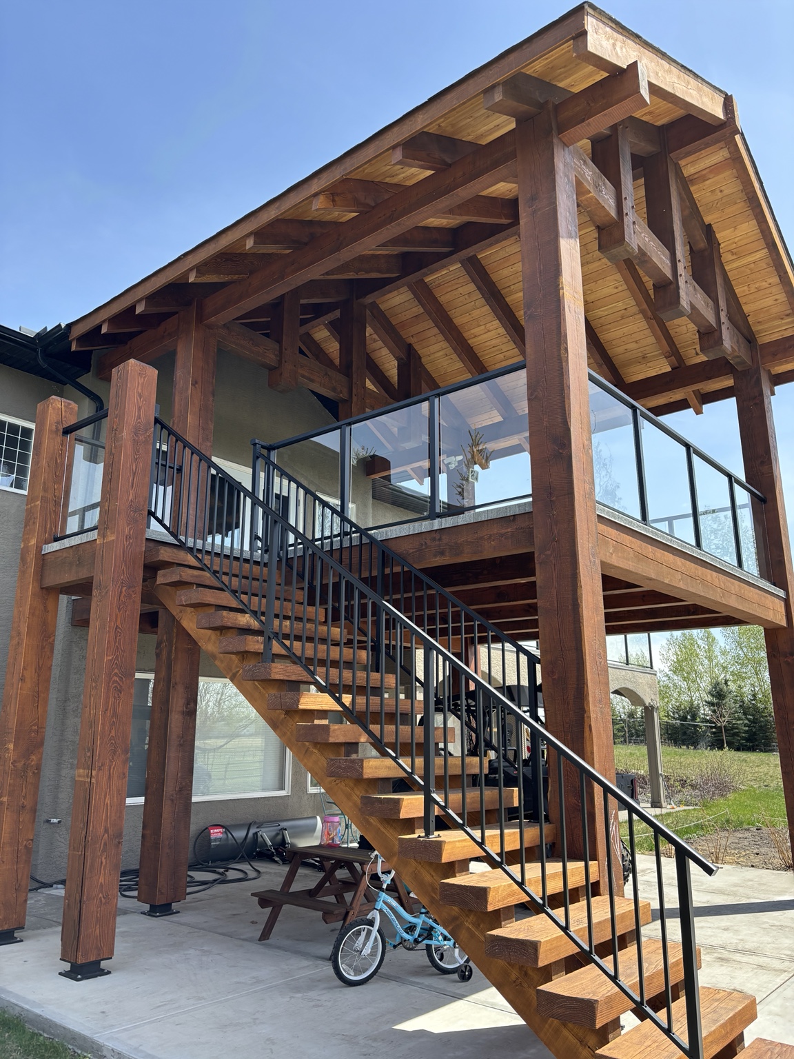 Custom timber covered deck with glass railing and black stair railing