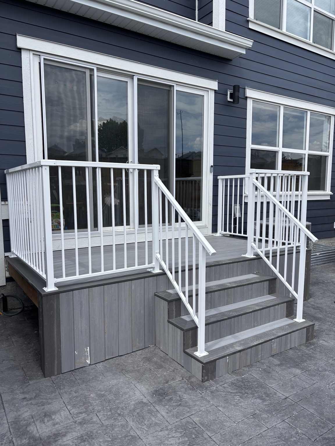 Grey entry deck with fitted white aluminum railing and stairs